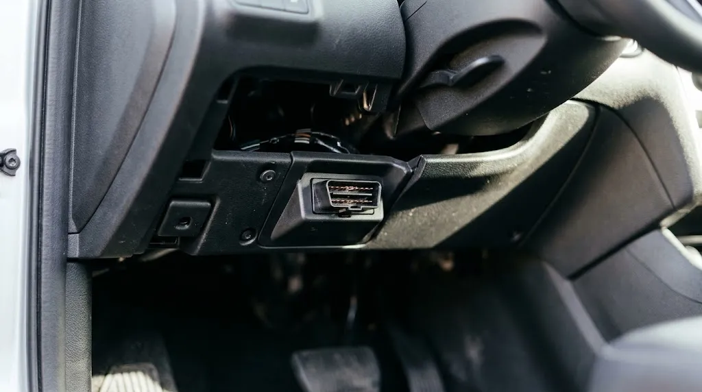Close-up of OBD2 diagnostic port under vehicle dashboard.